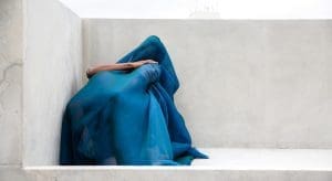 Foto aus der Ausstellung Hybris. Zwei Menschen unter einem blauen Tuch.